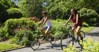Two women cycling on a path out in the sun © Joolze Dymond