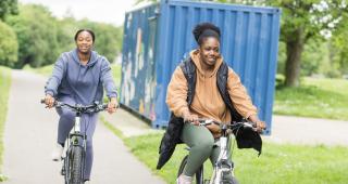 Two women cycling in a park smiling