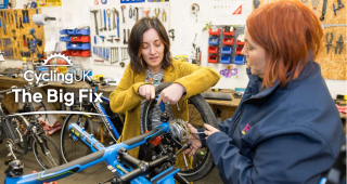 Two woman performing maintenance on a bike together