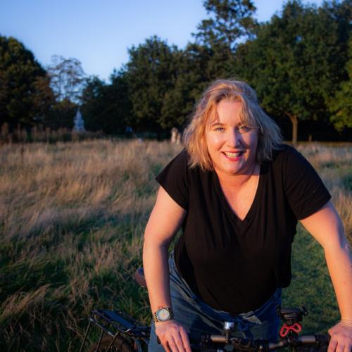 Carla is facing the camera with her bike in a park. She is wearing black T-shirt and jeans. Photo: Graham Berry.
