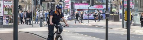 Man cycling on a cycle lane through an urban built up area
