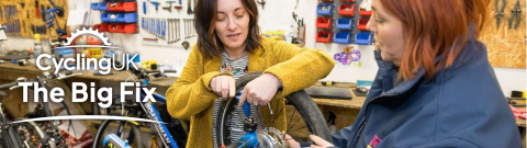 Two woman performing maintenance on a bike together