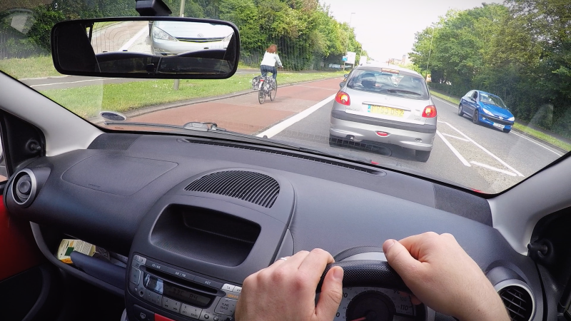 A driver stuck in traffic sees a cyclist go by in the bike lane.