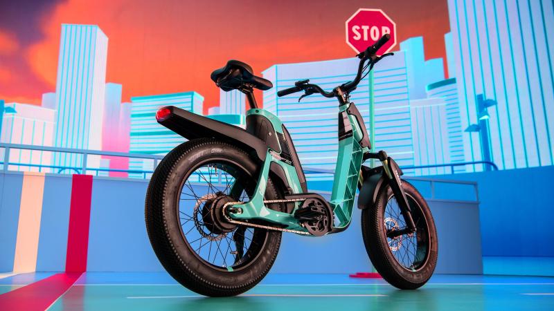 A turquoise and black e-bike with fat wheels in a staged urban environment that's multicoloured