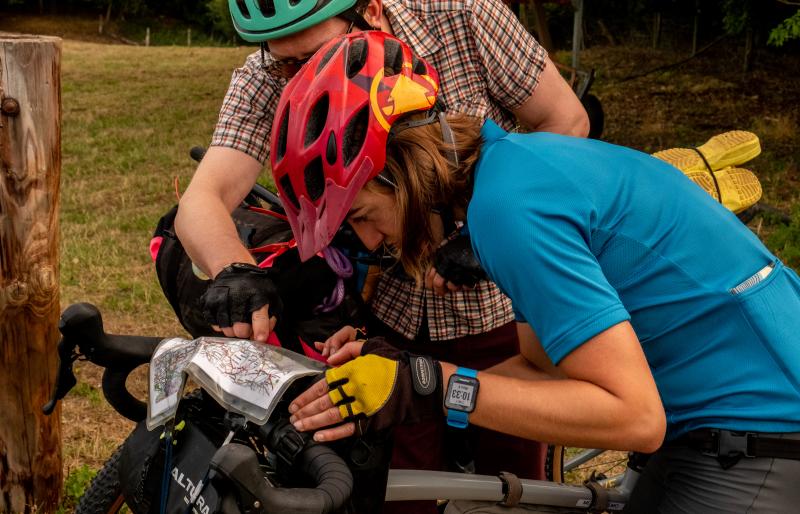 Two people standing with bikes peer over a map