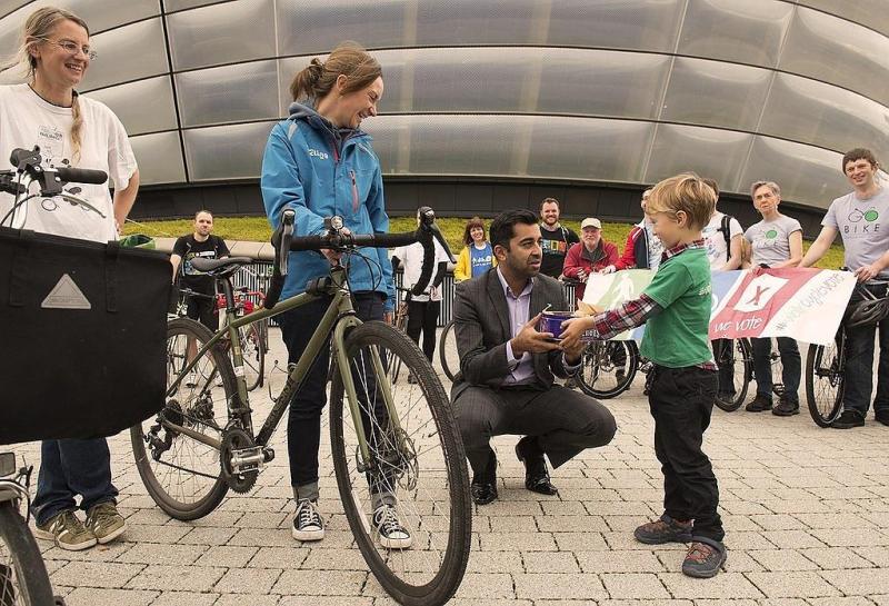 Suzanne (second from left) and her son (right) presenting a cake from WalkCycleVote cycle campaigners to the (then) Minister of Transport