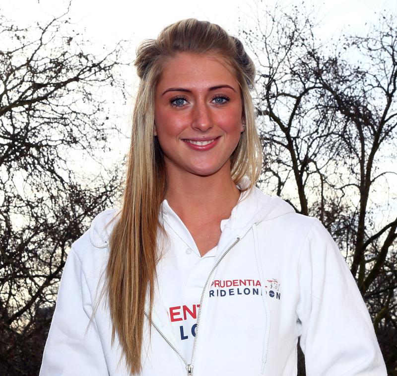 A woman with long blonde hair is smiling at the camera. She is wearing a white hoodie branded with Prudential RideLondon