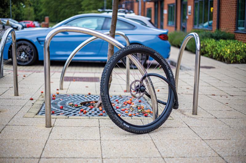 A bike wheel is locked to a cycle hoop in an urban setting. The bike it belongs to has been stolen