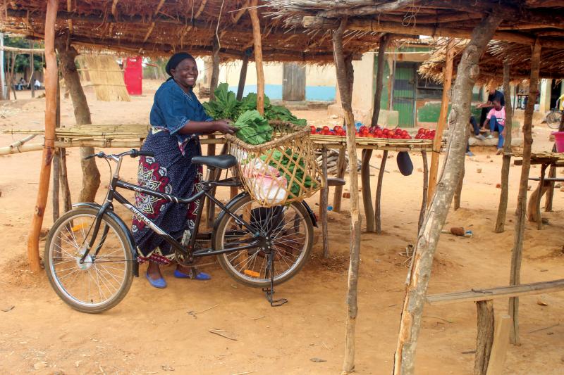 A woman is loading the rear basket of her Buffalo bikes with green leafy vegetables