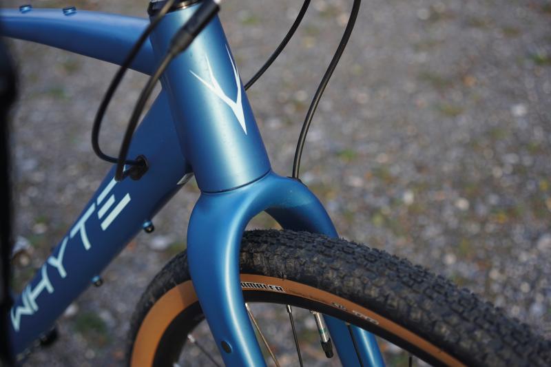 A close-up of the front fork and wheel of the Whyte, a metallic blue gravel bike