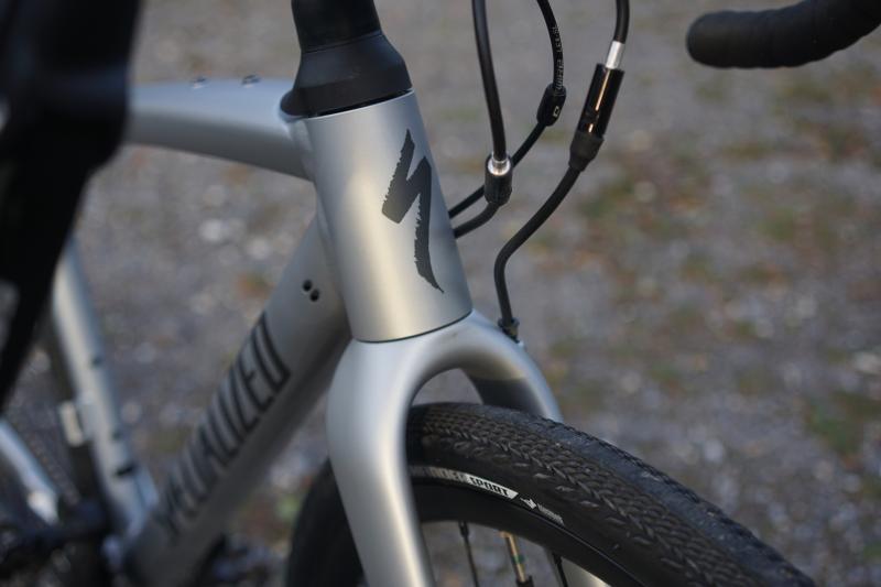 A close-up of the front fork and wheel of the Specialized, a grey gravel bike