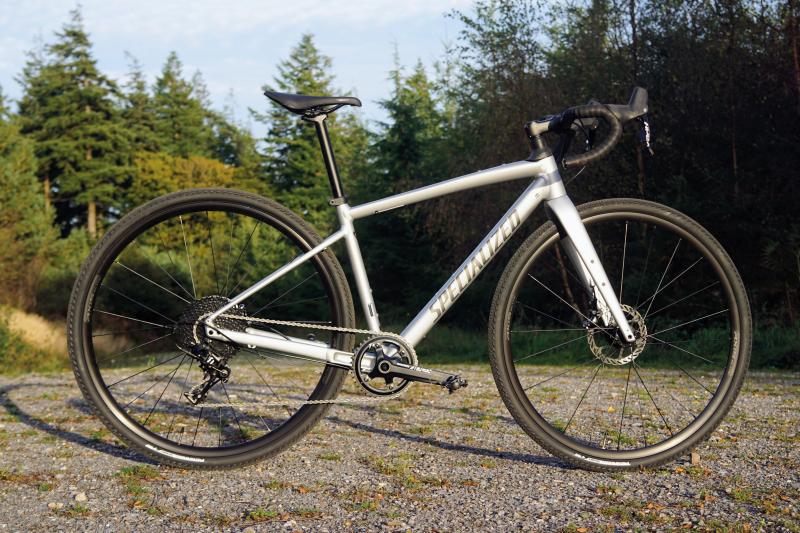 A grey gravel bike propped up on an off-road gravel track
