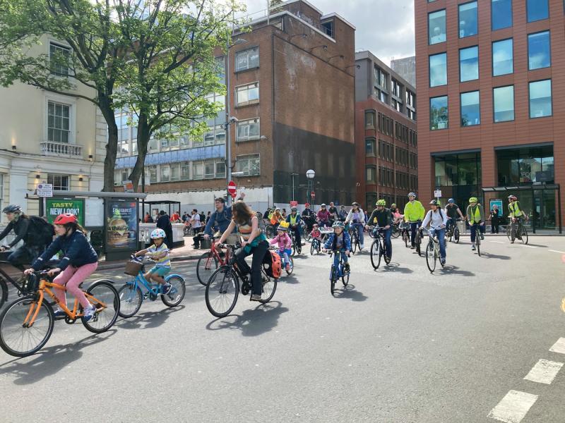 Adults and children cycling together on the road at a Kidical Mass cycling event