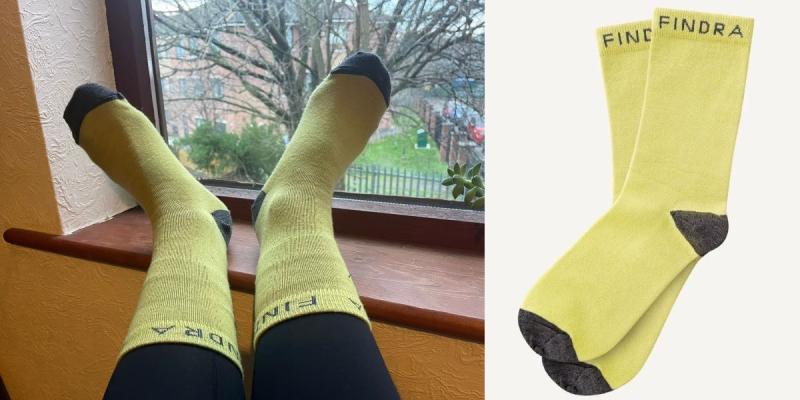 A composite image of Findra Skye Merino Block Colour Socks, with someone wearing them while putting their feet up on the windowsill on the left and a product shot of the bright yellow with grey toes and heels socks on the right.