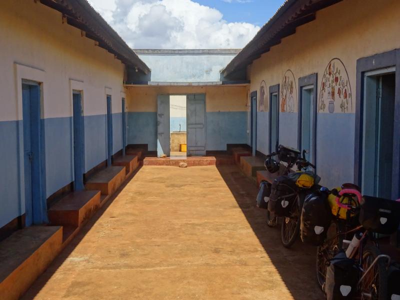 A courtyard with entrances to rooms in a guesthouse in Africa. One of them has two packed touring bikes outside