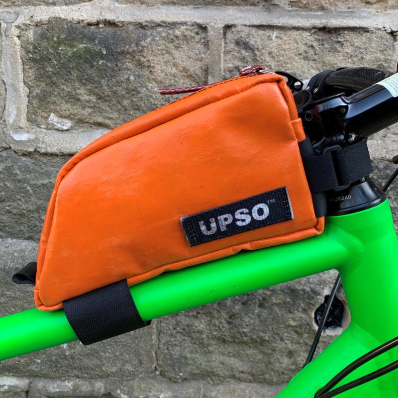 A bright orange bag is attached to the top tube of a green bike