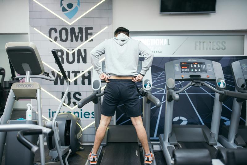 A man is standing on a treadmill during sports training in a gym