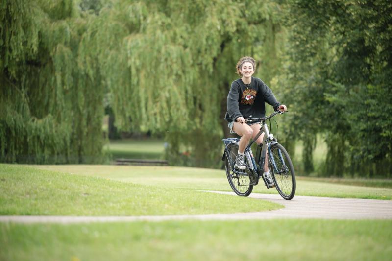 A woman riding an ebike through a park