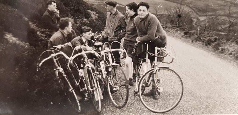 An old photograph of a group of young people stopped at the roadside while cycling in the 1950s