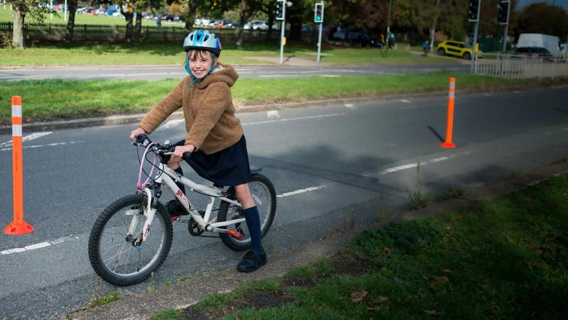 Young girl smiling on a bike cycling along a temporary cycle lane marked with cones