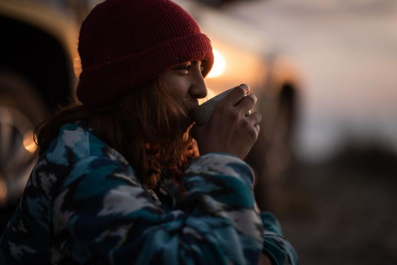 A woman sups on a hot drink in the cold