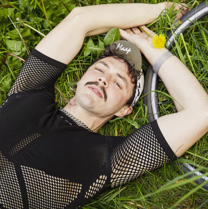 A person in cycle clothing lying down in the grass