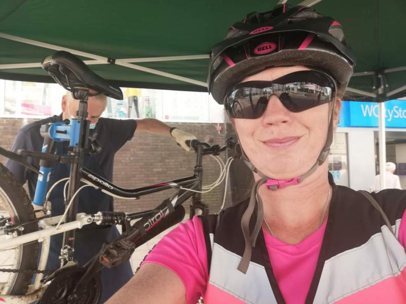 A smiling woman wearing a cycle helmet and pink top