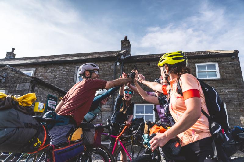 Several bikepackers high-five after finishing their ride