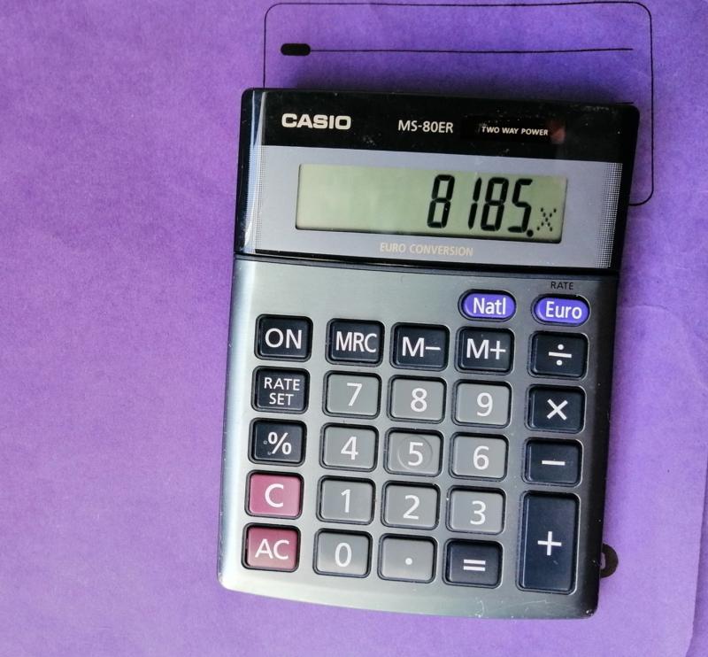 A calculator displaying the value 8185 placed atop a purple folder