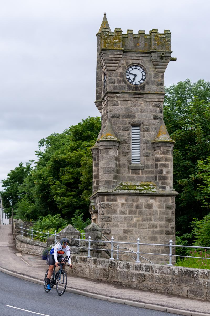 A woman rides past a church on a road