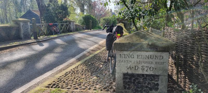 Bike propped against a stone engraved with the words &quot;King Edmund taken prisoner here A.D. 870&quot;