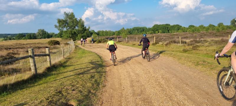 Two people cycle along a gravel track