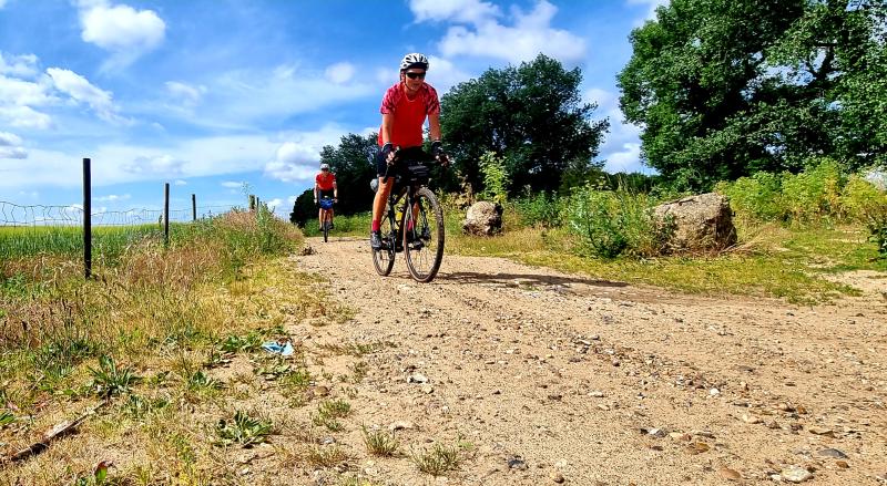 A woman laughs as she cycles on a sandy track