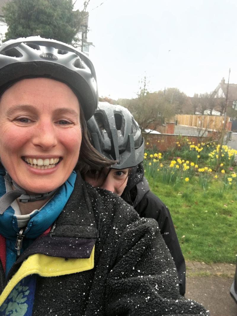A woman and her child, both wearing helmets share a selfie in the snow