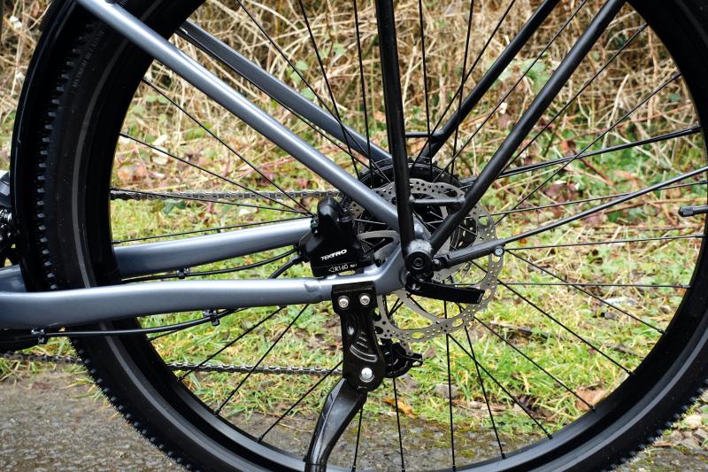 The rear wheel of a bicycle which showcases the disc brakes and kickstand
