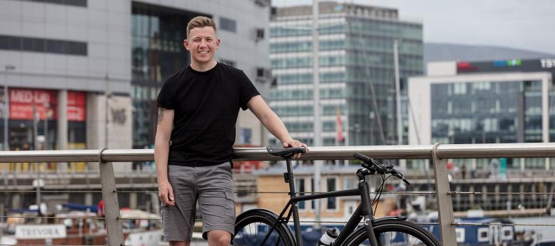 Man standing with bike on an urban bridge