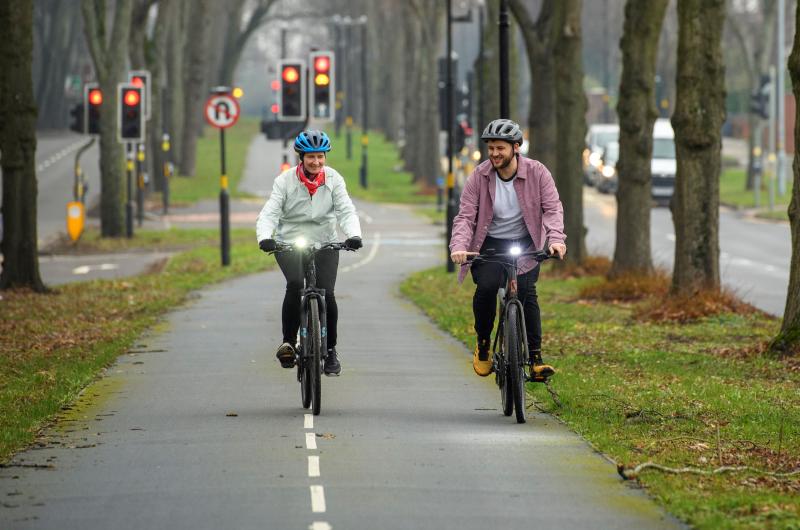 Two cyclists cycle together along a segregated cycle path in Birmingham