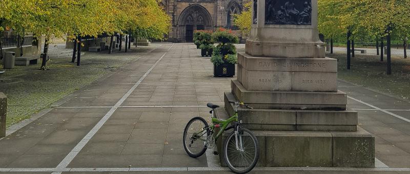 bike sitting against the base of a monument in a city centre