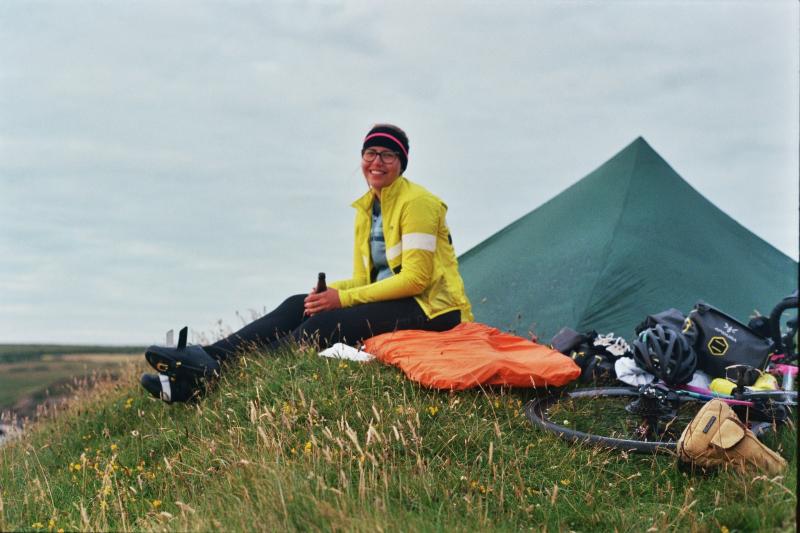 A woman sits by her tent