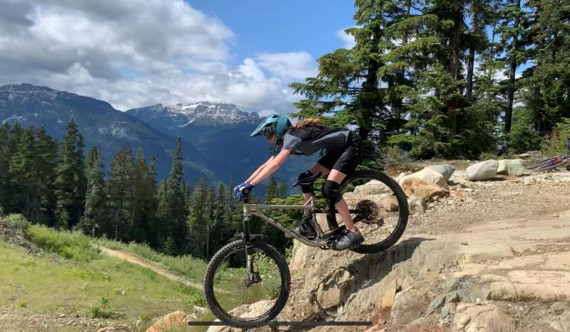Eme tackling a rock drop in Whistler, Canada, with the Rockies in the background