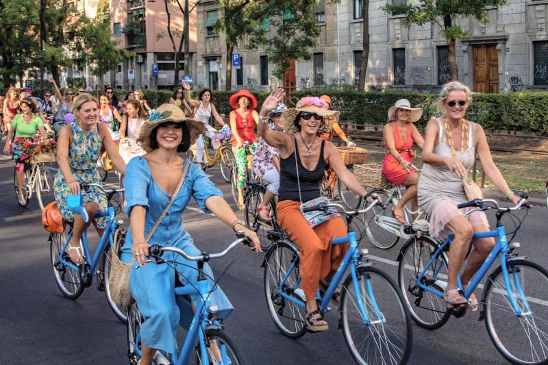A group of women in fancy clothes cycling and smiling at the camera  Photography by GGA