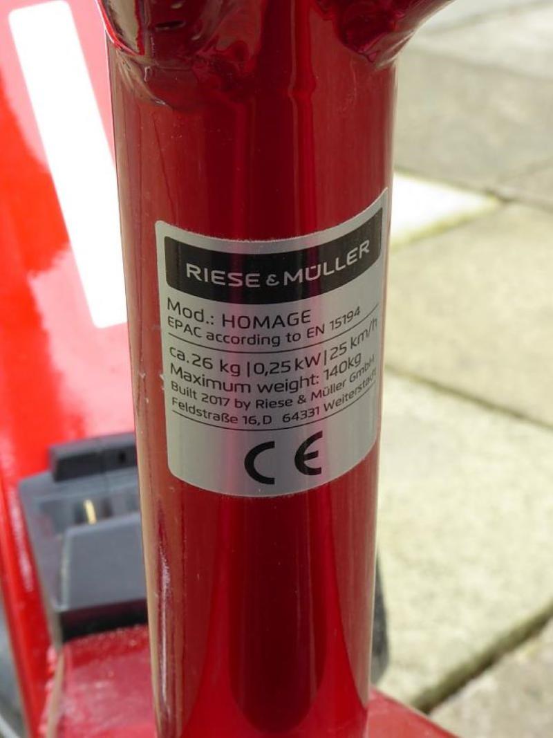 A close up of a white label on the frame of a red bicycle