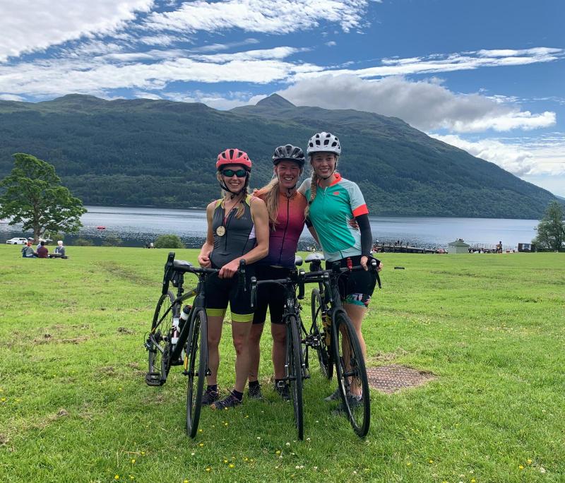 The three Guinness World Record holders posing with their bikes, a Lake District landscape behind them