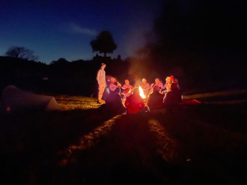 A group of bikepacking pals gather around a fire