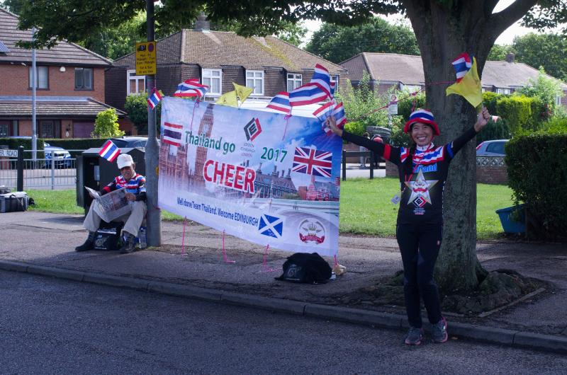 A woman is cheering the Thai team on in a street in Edinburgh along the route