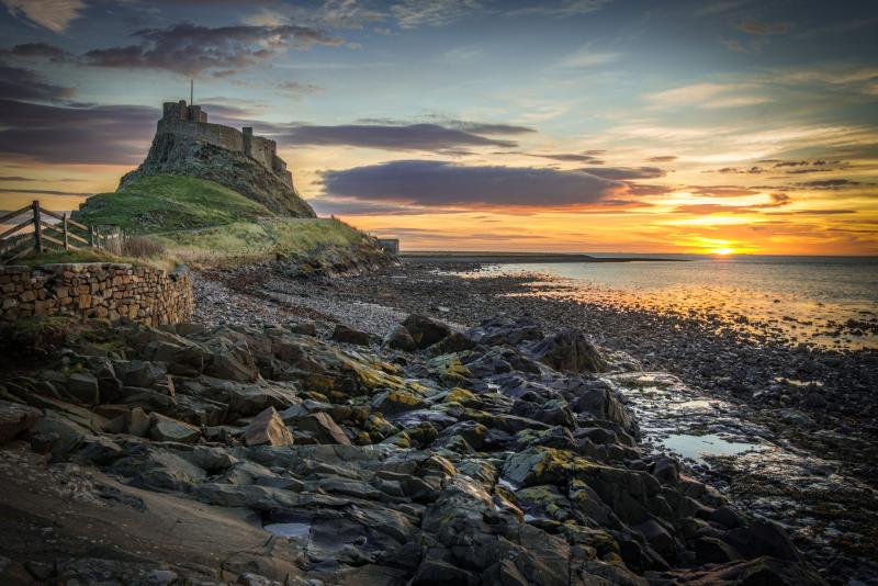 Castle on a high hill on an island, with a rocky coastline in the foreground