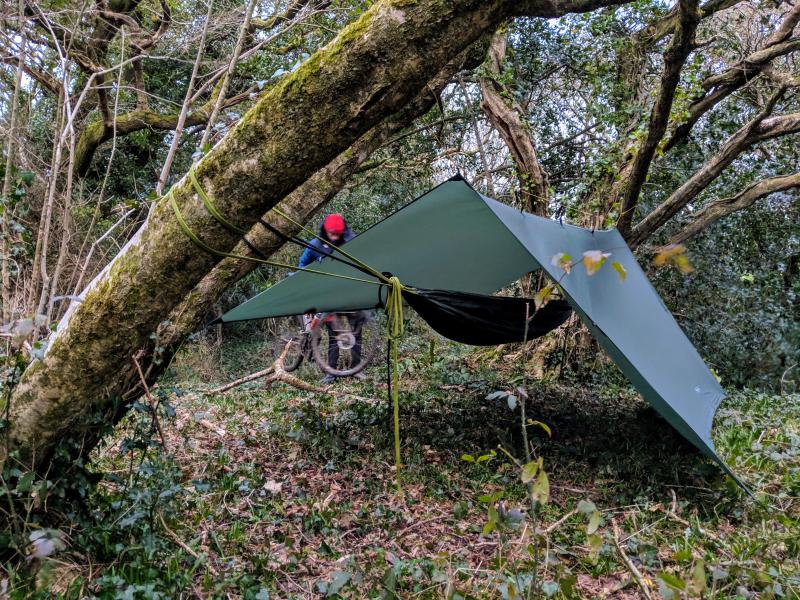 A hammock set up with a tarp to cover.