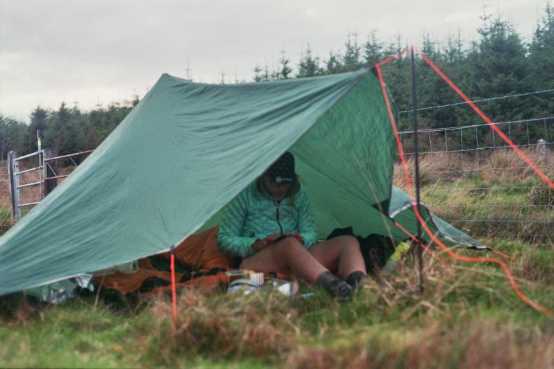 A cyclist changes under their tarp