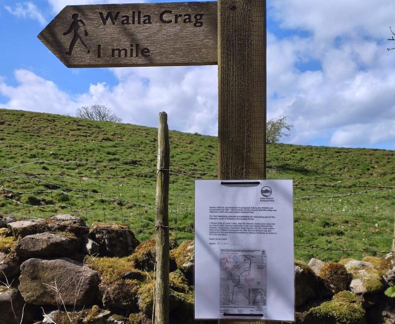Fingerpost saying 'Walla Crag 1 mile' with a paper sign attached to it advising people of a right of way application