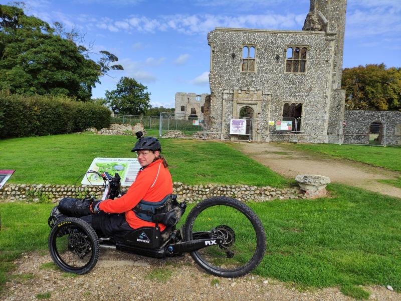 Man sitting on a three-wheeled handcycle in front of a ruined castle